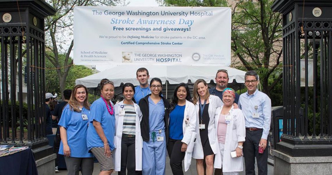 Group of fellows in front of a Stroke Awareness Day banner on campus